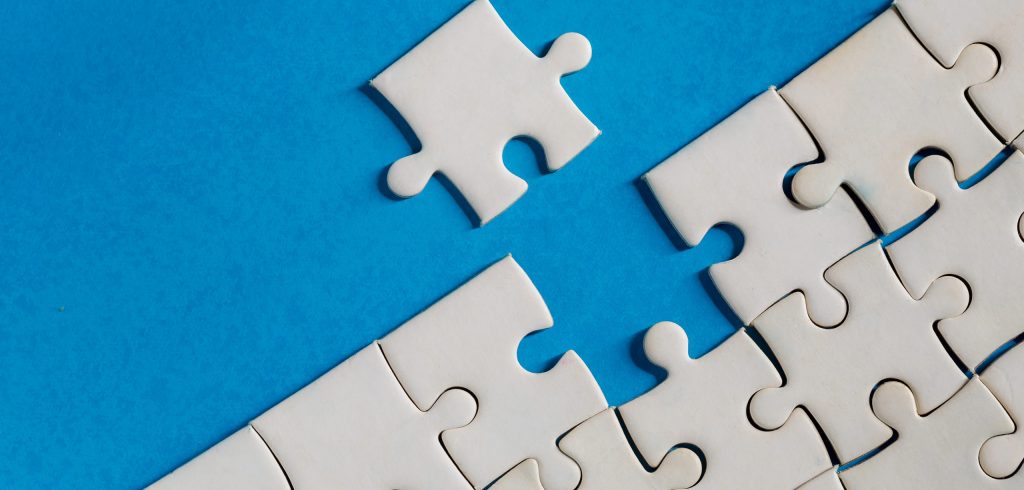 Unfinished red with white jigsaw puzzle pieces on blue background